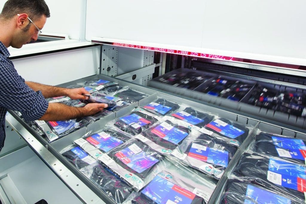 Worker retrieving inventory from vertical lift module tray