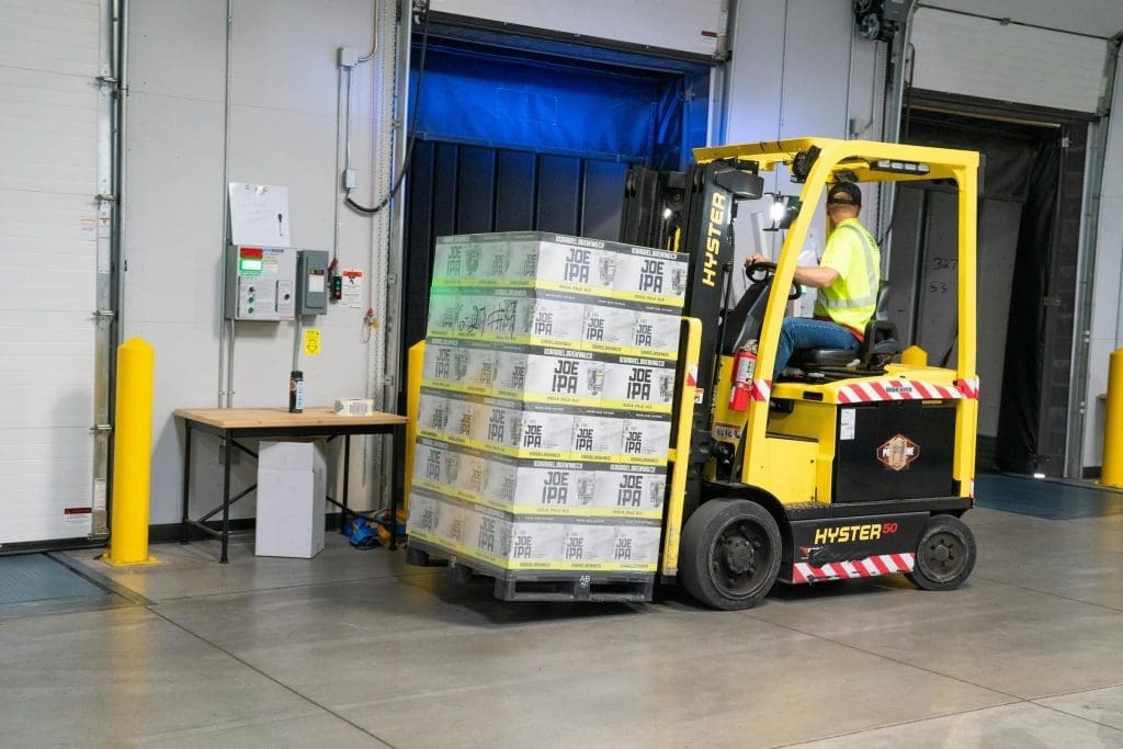 Forklift moving inventory inside manufacturing warehouse